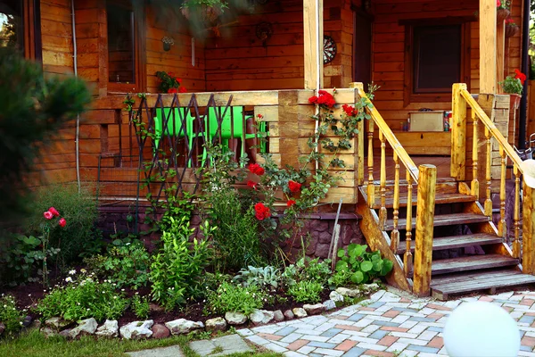 Wooden cottage house porch and  tile path in the summer blossoming garden