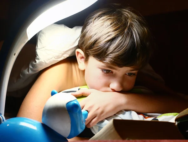 Preteen handsome boy read book with lamp