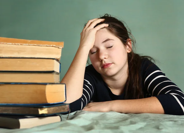 Tired teenage girl sleep among books