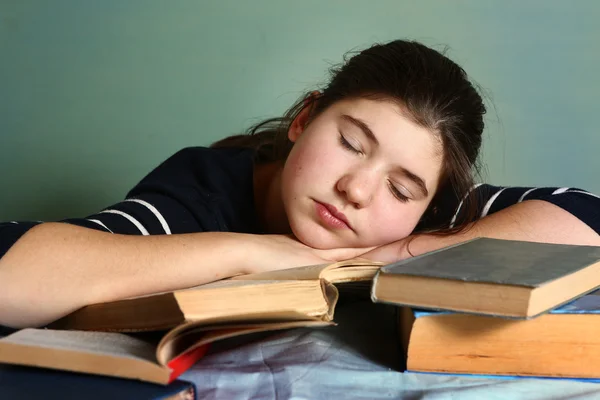 Tired teenage girl sleep among books