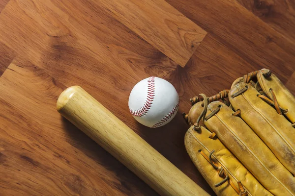 Baseball bat with ball and baseball glove on wood background