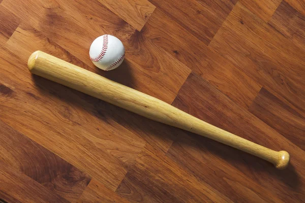 Baseball bat with ball and baseball glove on wood background