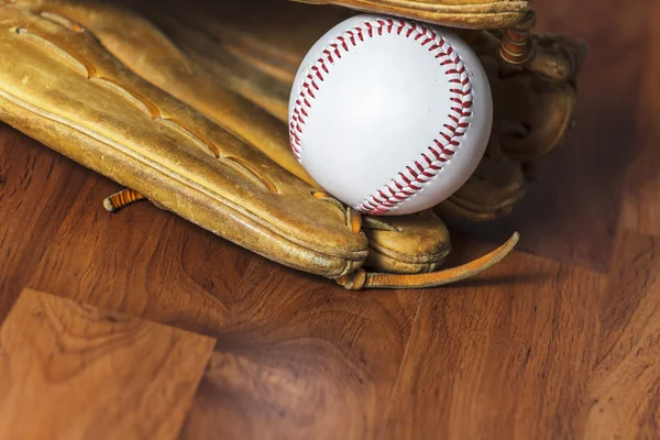 Baseball bat with ball and baseball glove on wood background