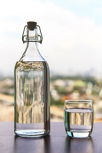 Glass of water with a bottle on table