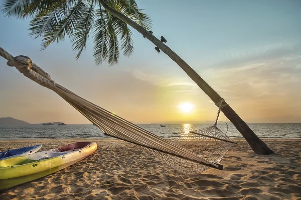 Sunrise with coconut palm trees and hammock on tropical beach background at Phayam island in Ranong province, Thailand