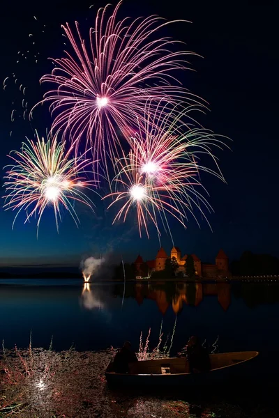 Big colorful fireworks explode with nice reflection on a water, July, Independence, fireworks with old castle in the background