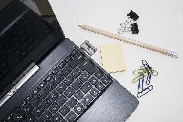 Workspace with laptop, mobile, clips, pencil, post it over white