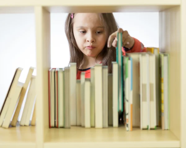 Young girl looking at books on bookshelf