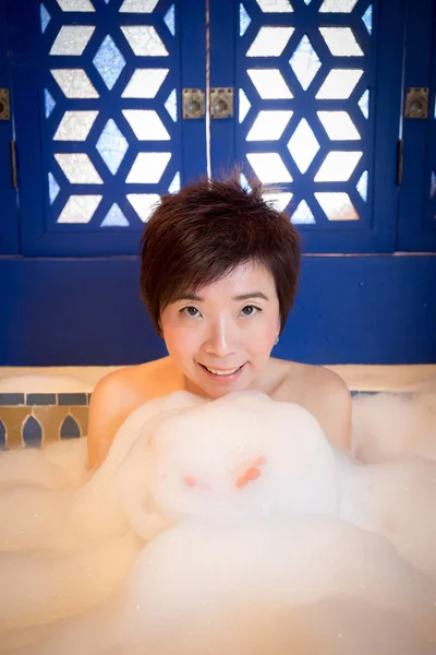 Beautiful young woman takes bubble bath