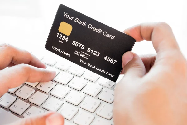 Hand holding a credit card and typing. On-line shopping on the i