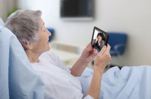 Female patient in hospital ward using digital tablet