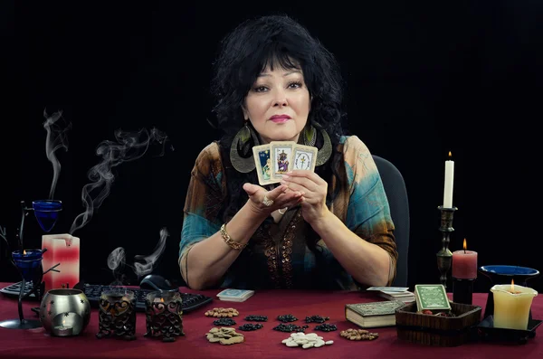 Modern gypsy witch sits at the desk with fortune telling cards