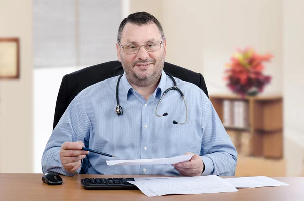 Male doctor in glasses reading laboratory results