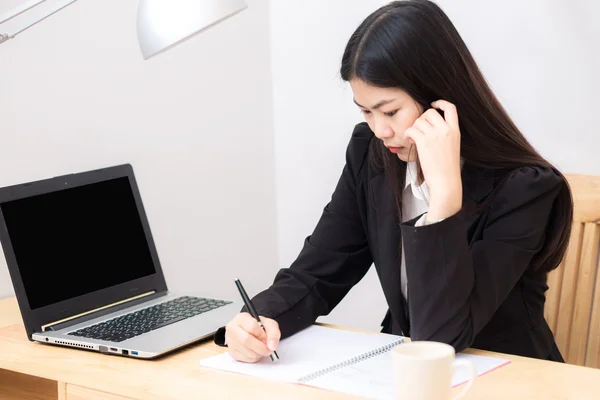 Portrait of business asian woman with laptop writes on a documen