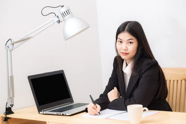 Portrait of business asian woman with laptop writes on a documen