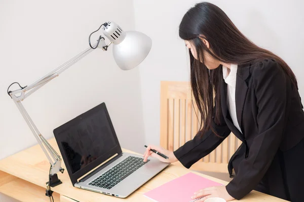 Portrait of business asian woman with laptop writes on a documen