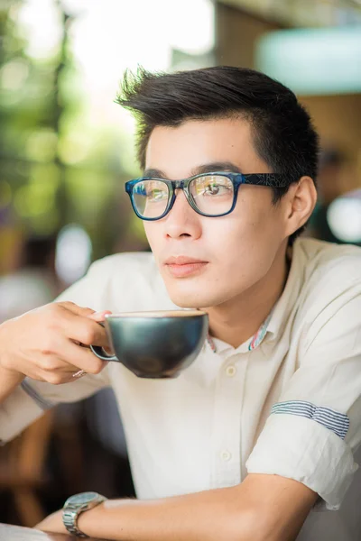 Asian smiling man with cup of latte art coffee indoor