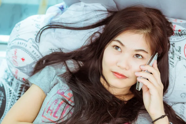 Woman in bed checking social apps with smartphone