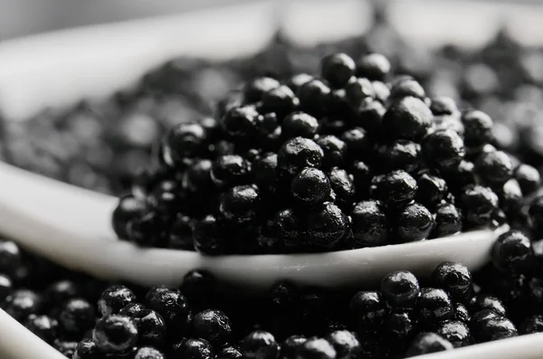 Spoon of black caviar close-up in a heap of black caviar