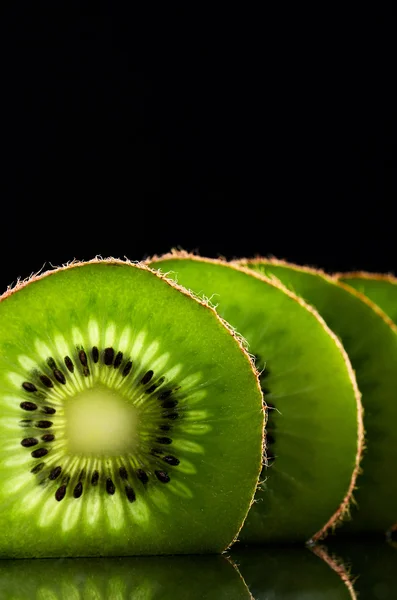 Cut slices of kiwi fruit close-up on black background vertical.