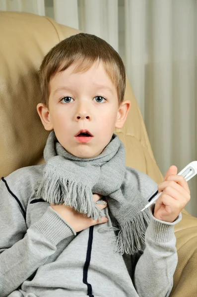 Boy coughing and holding a thermometer