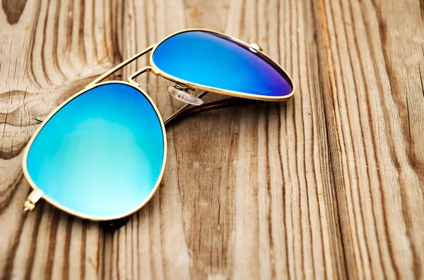 Blue mirrored sunglasses on the wooden background close up