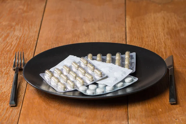 Variety of pills on plate with fork and knife