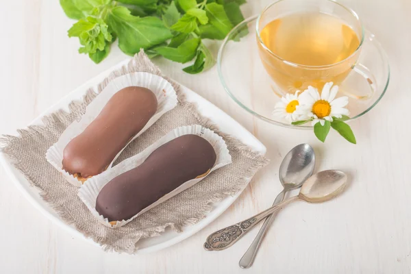 Cup of chamomile tea with chocolate eclairs