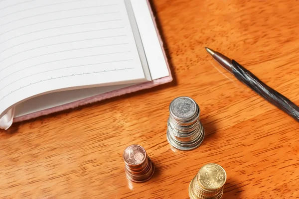 Open notebook with pencil and stacks of coins