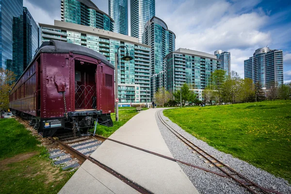 Railroad car at Roundhouse Park and modern buildings in downtown