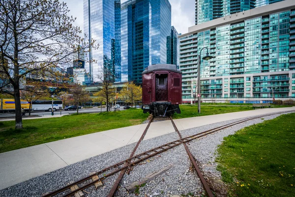 Railroad car at Roundhouse Park and modern buildings in downtown