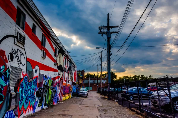 Graffiti and parked cars in an alley at sunset in Baltimore, Mar