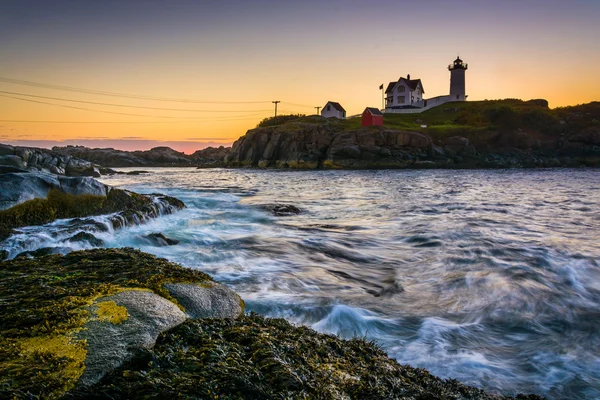 Waves splashing on rocks and Nubble Lighthouse at sunrise, at Ca