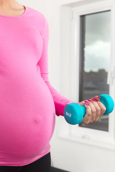 Pregnant woman exercising with training weights