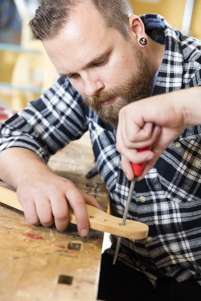 Close-up of craftsman files wooden guitar neck in workshop