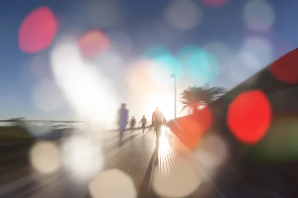 People in bokeh, sunset street with palms