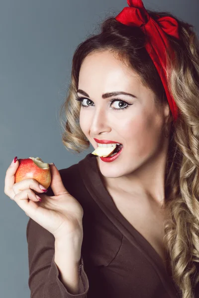 Portrait of beautiful young sexy blonde with a red armband with red lips with an apple, biting apple, healthy lifestyle, sensual temptation to make up pin up