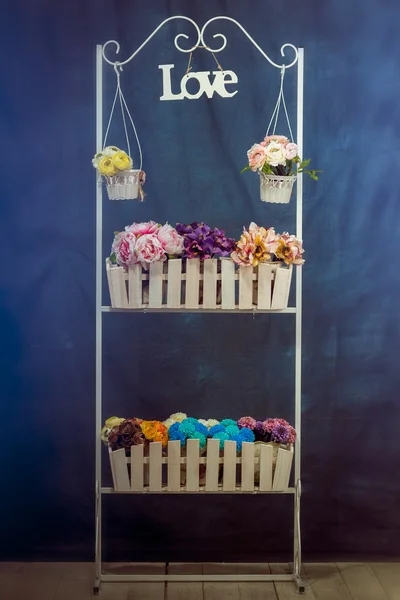 Stand with flowers, flowers on the table wooden desk with artificial flowers, fence