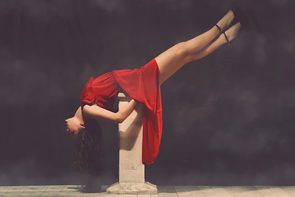 Young beautiful and charming girl in red is dancing with a slender figure plastic body dancer with hair gymnast performs twine curly ringlet