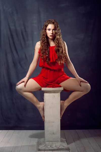 Young beautiful and charming girl in red is dancing with a slender figure plastic body dancer with hair gymnast performs twine curly ringlet