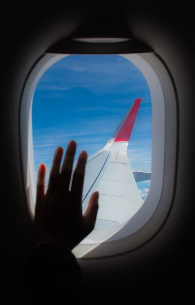 Silhouette of passenger hand touch window of airplane.