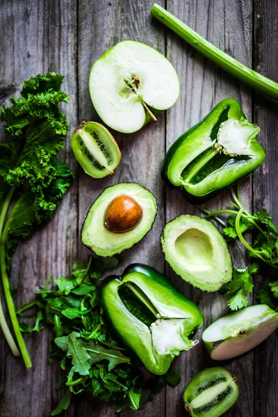 Mix of green vegetables and fruits on rustic background