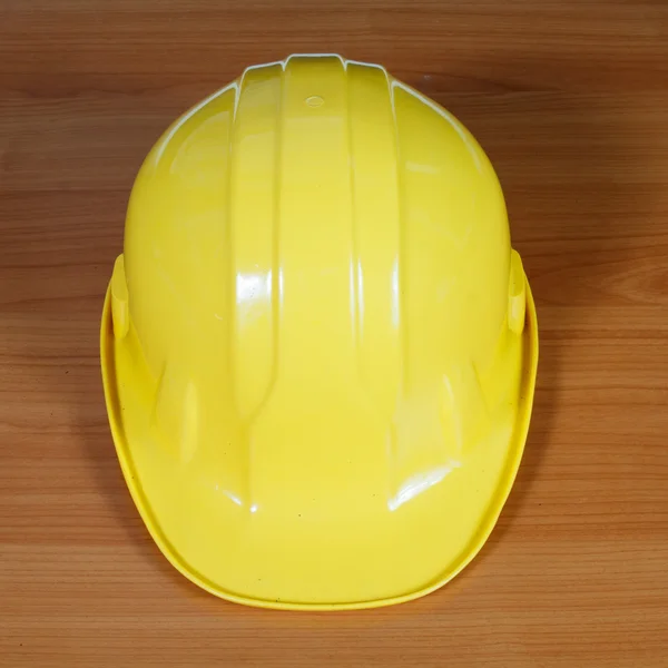 Yellow safety helmet on wooden background