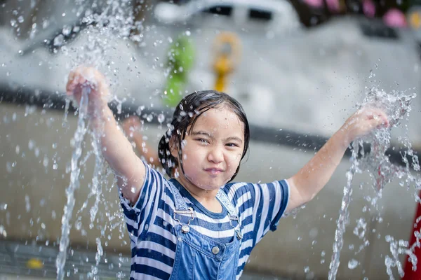 Asian girl playing with water fountain at water park