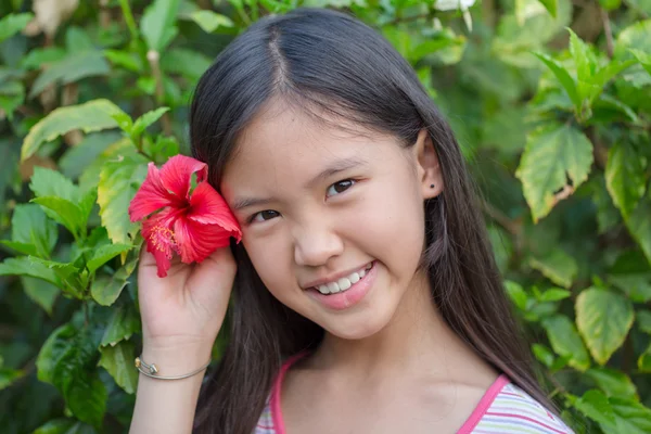 Little Asian girl smiling with Chinese rose in the garden