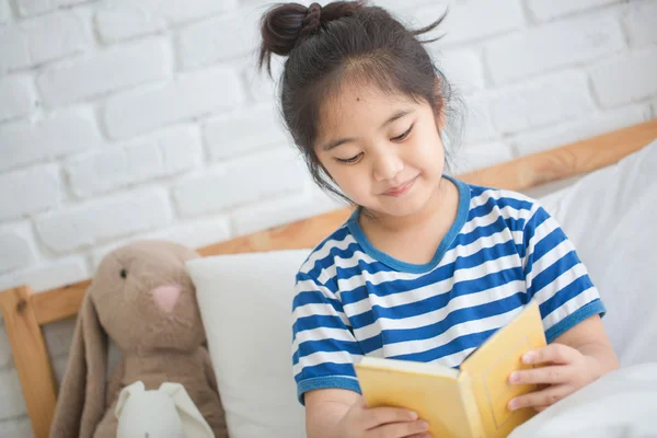 Happy Asian girl reading story book on the bed