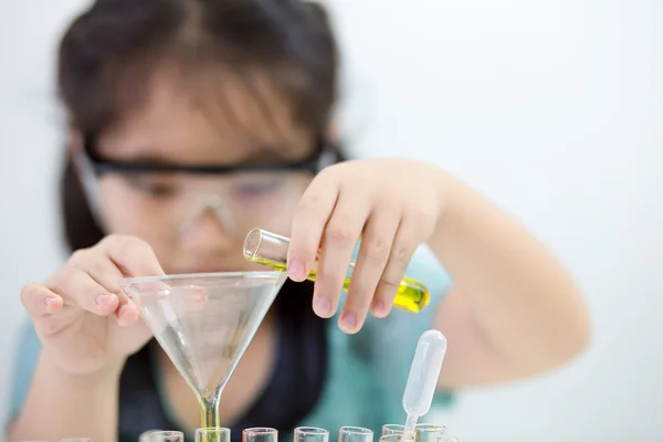 Little Asian student girl with protection glass making science experiment in the laboratory room