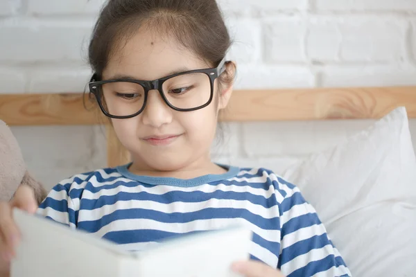 Happy Asian girl reading story book on the bed