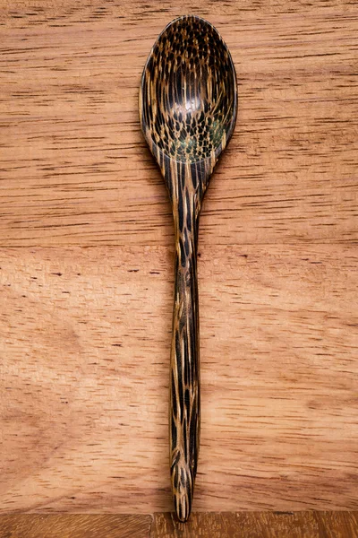 Wood spoon on wood background dark brown.