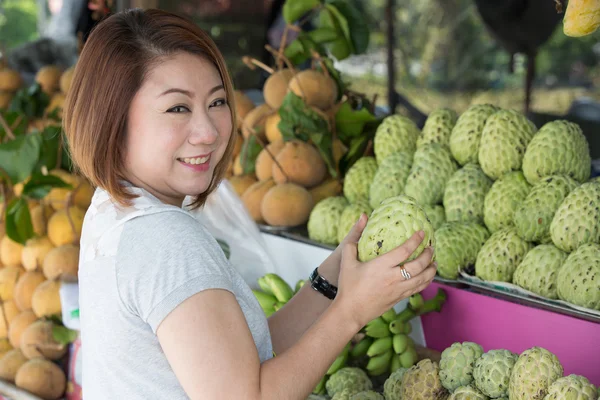 Happy asian woman choosing fresh custard apple fruit